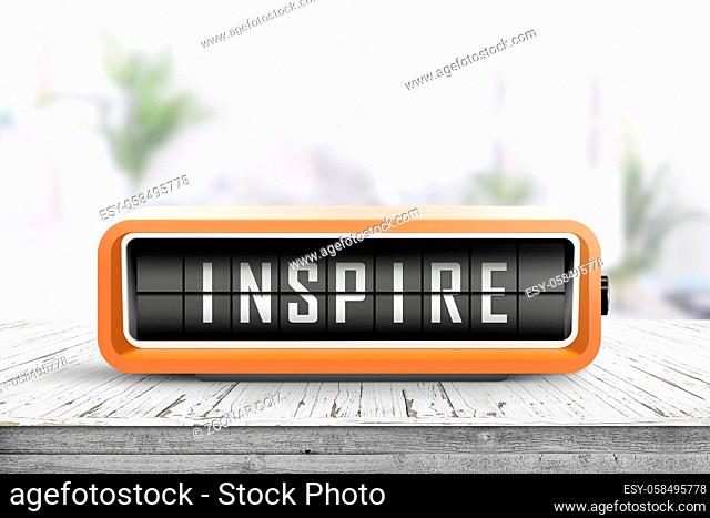 Inspire message on a retro alarm device on a wooden table in a bright room