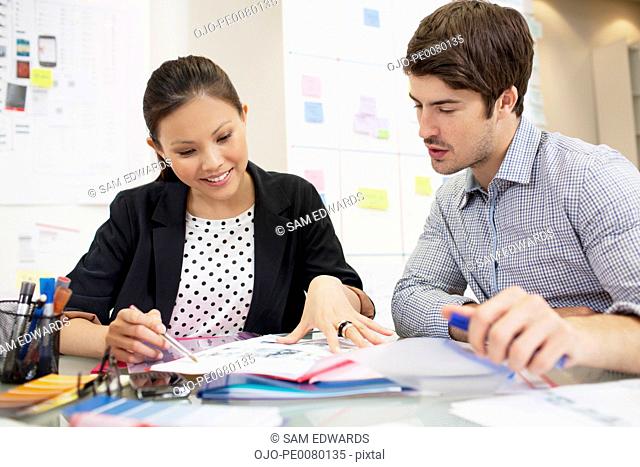 Businessman and businesswoman reviewing paperwork in office