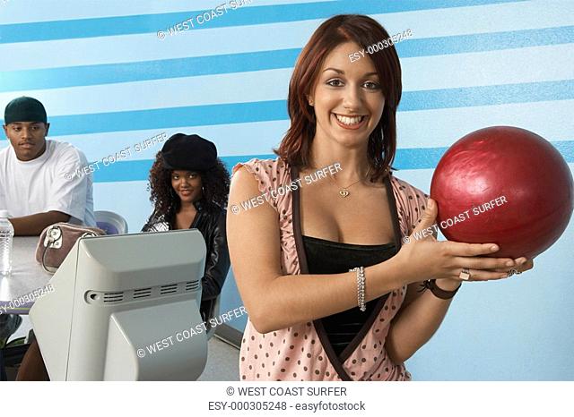 Young woman at bowling alley holding ball portrait