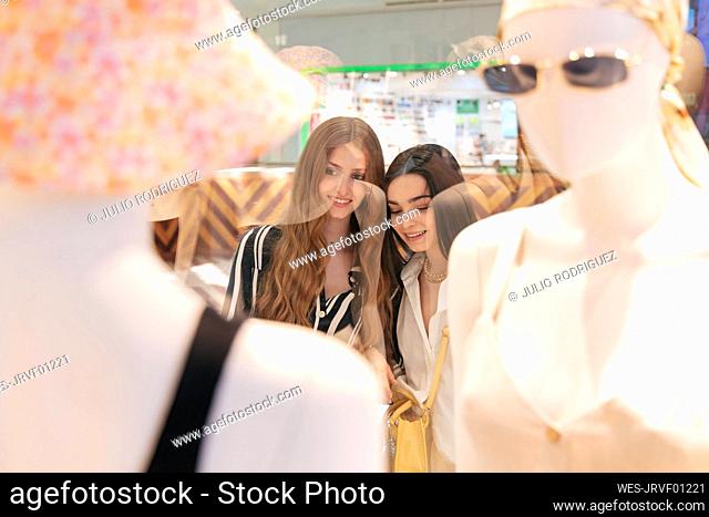 Smiling friends standing by store window