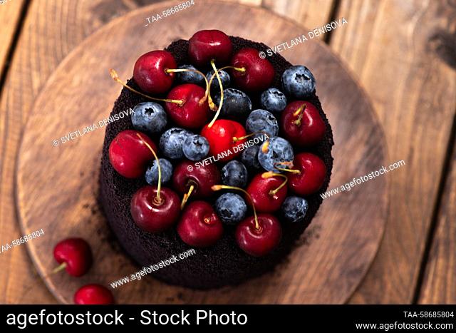 A cake decorated with berries on a wooden table. Svetlana Denisova/TASS