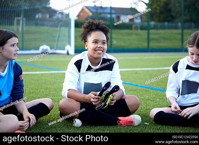 UK, Female soccer team sitting in field during training