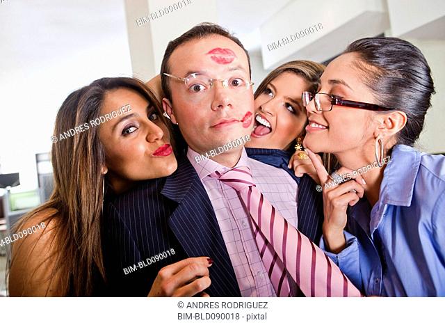 Businesswomen kissing male co-worker