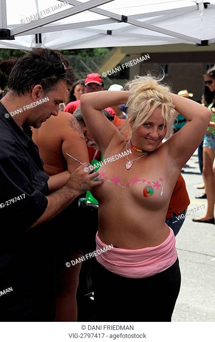 An artist paints a topless woman during Gay Pride festivities in Toronto, Canada. - TORONTO, ONTARIO, CANADA, 03/07/2011