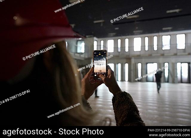 14 December 2023, Hamburg: A woman takes a photo of the sports and concert hall in the greened St. Pauli bunker on Heiligengeistfeld during a tour