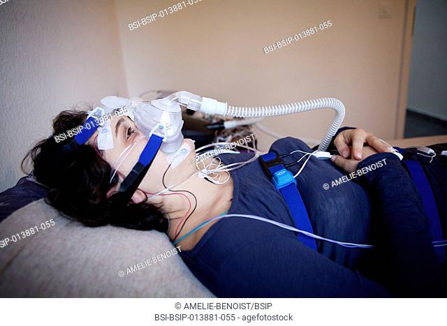 Reportage at cenas, a swiss sleep centre. a patient undergoes a polysomnography wearing a continuous positive airway pressure mask for sleep apnea