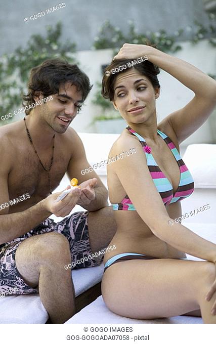 Man applying sunscreen to girlfriend's back