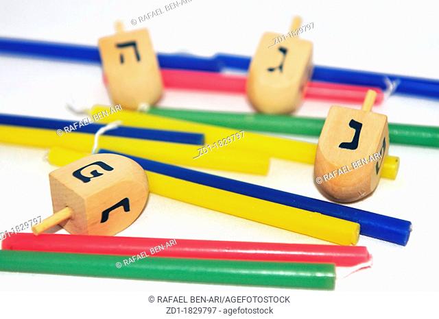 Photo of a dreidels spinning tops and colorful candles isolated on white - objects for the Jewish holiday of Hanukkah