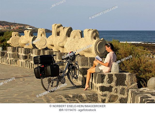 Female bicyclist in front of work of art, Medano, Tenerife, Canary Islands, Spain, Europe
