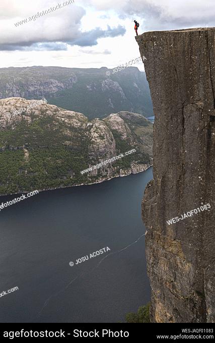 Hiker standing on edge of majestic Pulpit rock cliff by Lysefjorden fjord, Norway