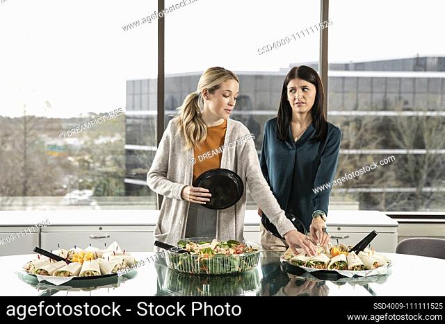 Two people reaching for the same item on a lunch buffet