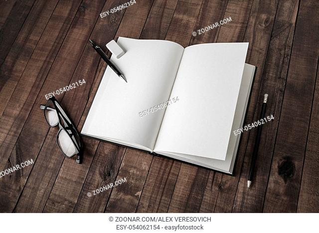 Blank open book and stationery on wood table background. Responsive design mockup