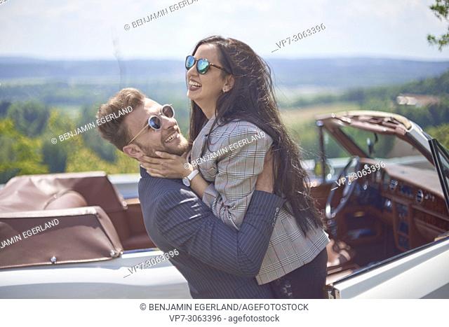 vibrant couple falling in arms in front of luxury oldtimer car. Turkish ethnicity. Blogger Adem Bayalan. Bavaria, Germany