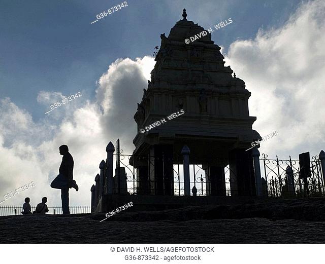 Visitors pass and exercise near a small shrine atop a large rock in the Lal Bagh park in Bangalore, Karnataka, India