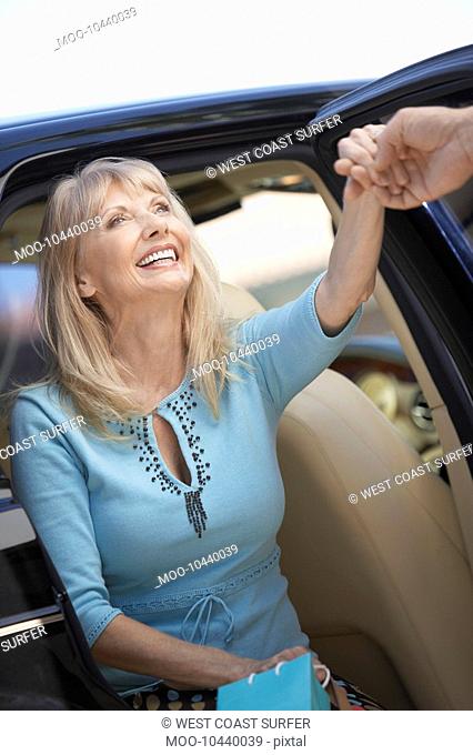 Smiling Woman getting out of car holding Shopping Bags