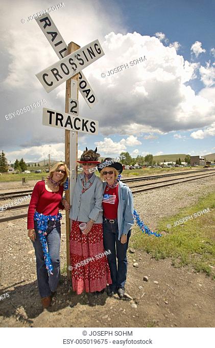 Three women at a railroad crossing dressed for the Fourth of July, in Lima Montana