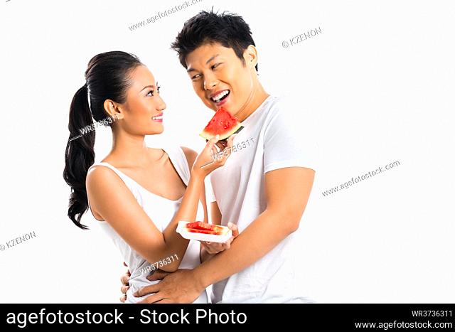 Young Asian couple eating fruits and having fun