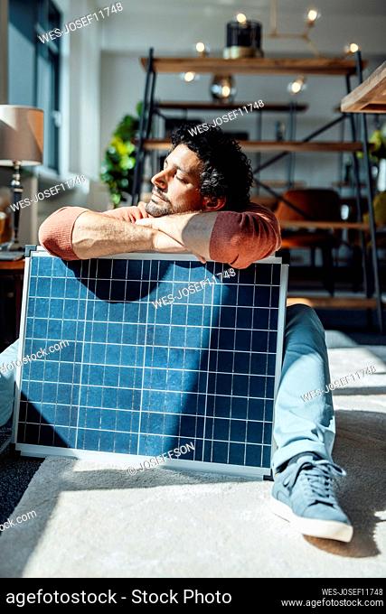 Businessman leaning on solar panel at workplace