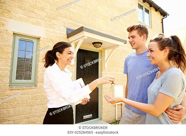 Female real estate agent giving keys to new property owners