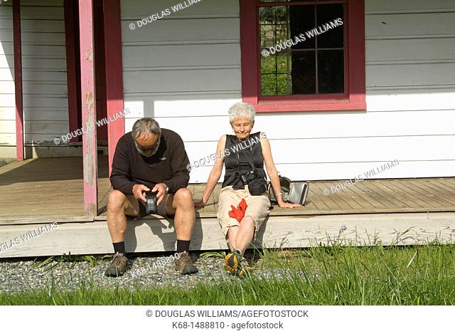 an older couple relaxes on the porch of a house