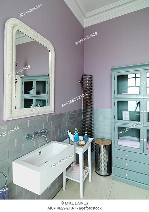 Mirror above washbasin in pink bathroom, UK home