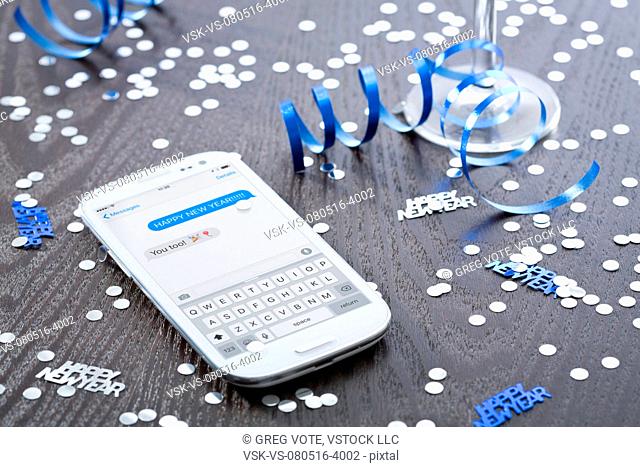 Cell phone among confetti on wooden surface