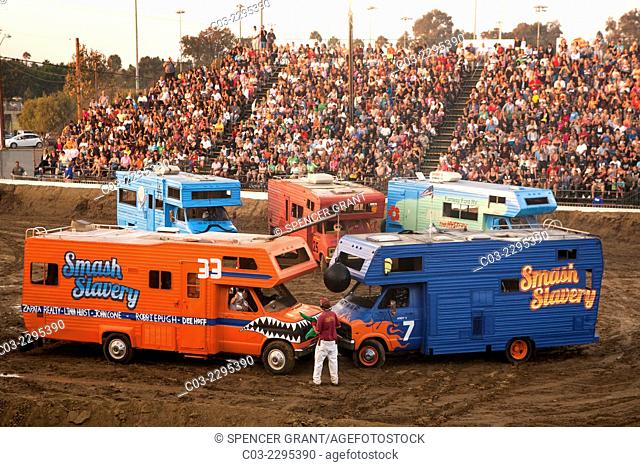 Brightly painted motor homes gather for a demolition derby at dusk at the Orange County Fair in Costa Mesa, CA. The object of the derby is for the vehicles to...