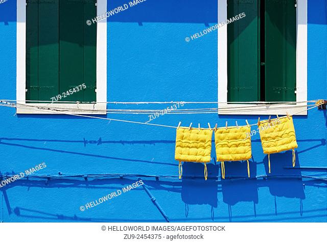 Three yellow cushions hanging on line outside blue painted house, Burano, Venetian Lagoon, Veneto, Italy, Europe