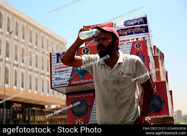 13 July 2023, Iraq, Baghdad: A man pours water over his face to cool down during a hot summer day at Al-Shorja market. Photo: Ameer Al-Mohammedawi/dpa