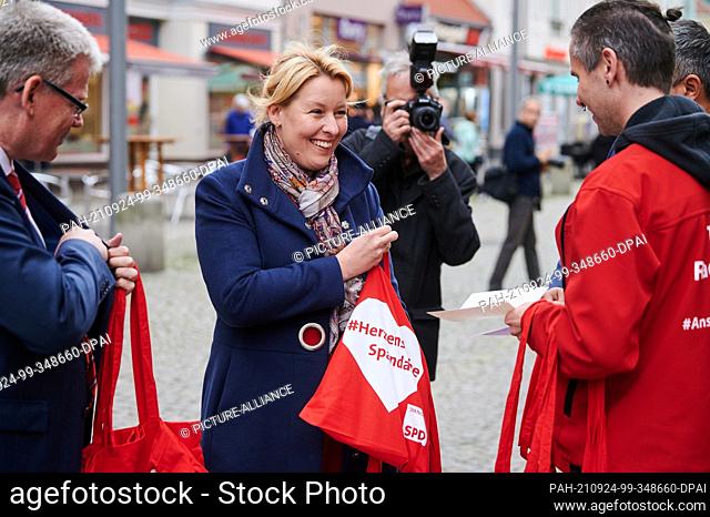 24 September 2021, Berlin: Top candidate Franziska Giffey (SPD) looks for an autograph pen while handing out red SPD bags with party colleague Helmut Kleeband