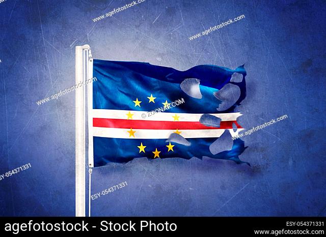 Torn flag of Cape Verde flying against grunge background
