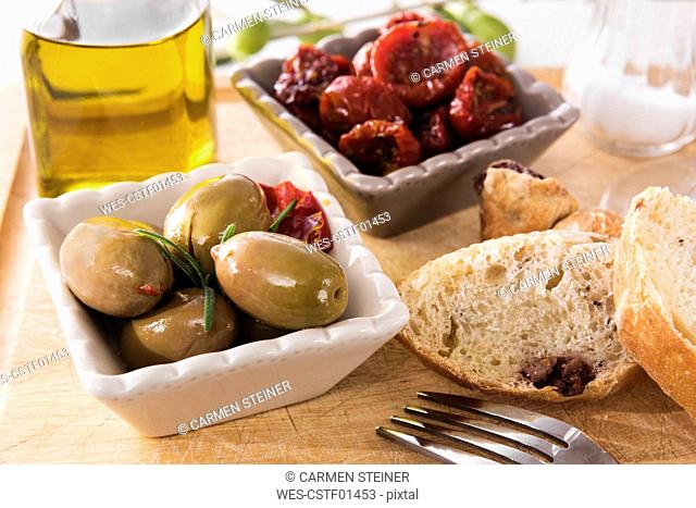 antipasti, pickled olives, pickled tried tomato, olive bread, olive oil and salt