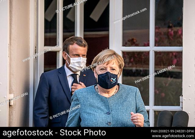 20 August 2020, France, Bormes-Les-Mimosas: Emmanuel Macron, President of France, comes behind German Chancellor Angela Merkel (CDU) to the press conference at...