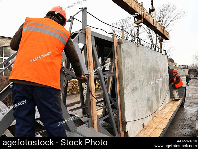RUSSIA, ZAPOROZHYE REGION - DECEMBER 19, 2023: Loading reinforced concrete structures onto a flatbed truck at a plant of reinforced concrete structures in the...