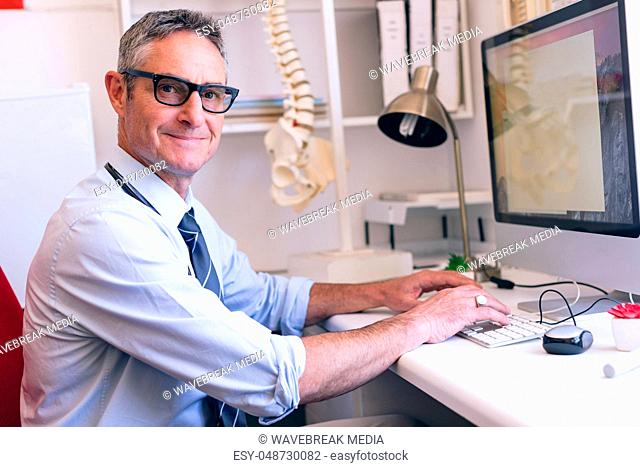 Confident male doctor working on computer at clinic of retirement home