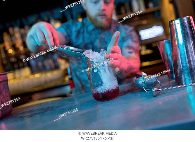 Bartender putting ice in jar while preparing cocktail