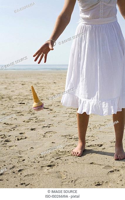 Woman dropping her ice cream on beach