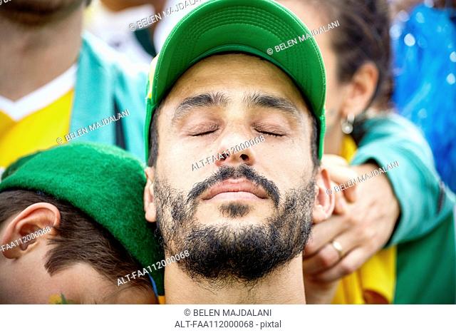 Football fan with head back and eyes closed in disappointment