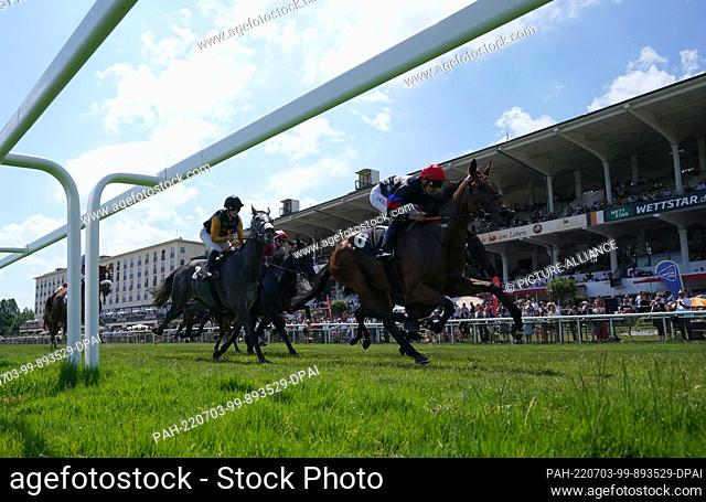 03 July 2022, Hamburg: Horse racing: Gallop, 153rd German Derby at Horner racecourse. Horses run past the main grandstand at Horner Rennbahn during a race