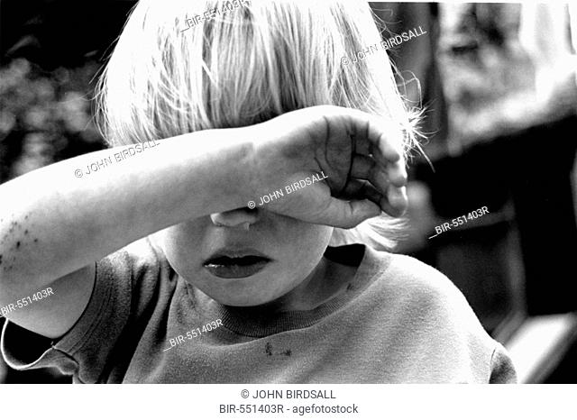 Young child shielding face with arm