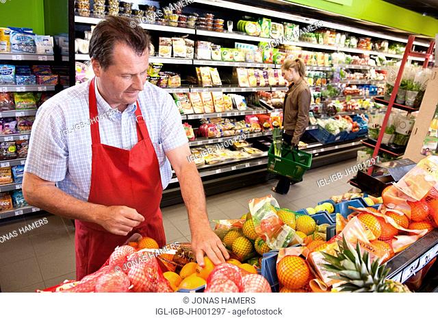 A supermarket employee arranges goods and food