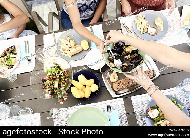Family eating together at table outdoors