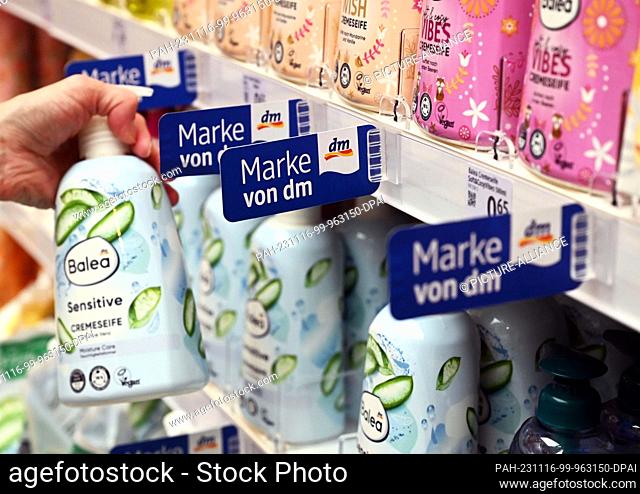 PRODUCTION - 10 November 2023, Baden-Württemberg, Karlsruhe: A person takes a product from the dm own brand Balea from a shelf in a branch of the drugstore...