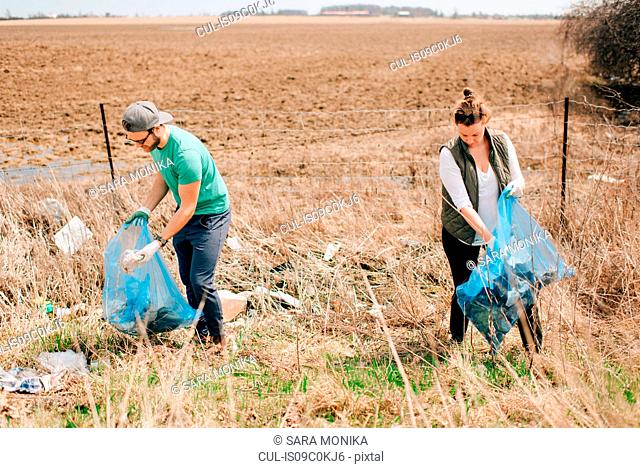 Couple picking up rubbish by field, Georgetown, Canada