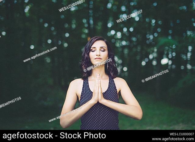 Young woman meditating with closed eyes in the forest, yoga in nature