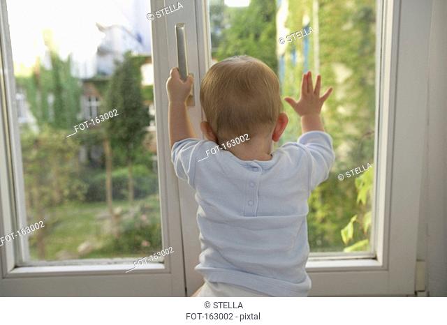 Rear view of a baby trying to open a window