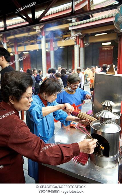 Temple functionaries help worshippers and visitors with incense and ceremonies at the Hsingtian Temple