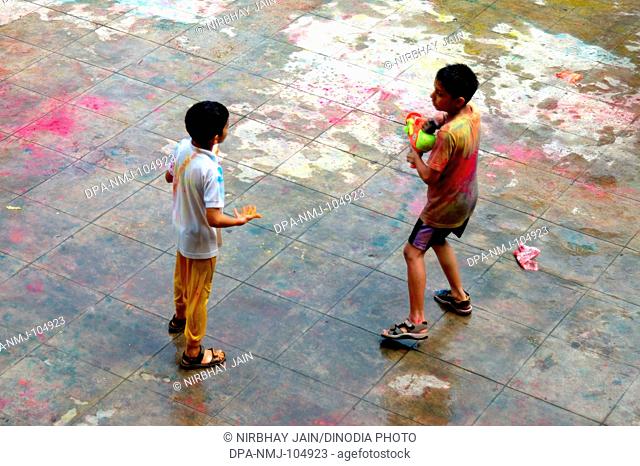 Two children playing Holi festival of color at Ananta apartments at Breach Candy  ; Bombay Mumbai  ; Maharashtra  ; India