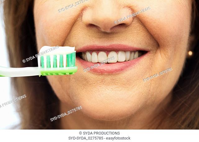 senior woman with toothbrush brushing her teeth