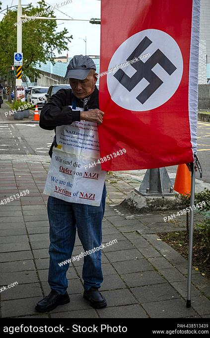 A protester stands with a flag emblazoned with the Nazi symbol in front of the European School in Taipei, Taiwan, on 13/12/2023